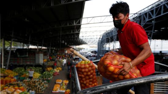 Un hombre descarga frutas de un camión de transporte en el mercado mayorista de Quito, el 10 de abril de 2021.