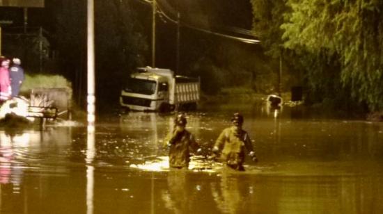 Dos bomberos caminan por las calles de Cuenca, tras el desbordamiento de un río, el 12 de febrero de 2022.