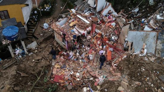  Fotografía tomada con un drone que muestra a dos hombres junto a una vivienda destrozada en Petrópolis, Brasil, el 19 de febrero de 2022.