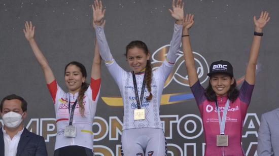 Esther Galarza (centro) levanta los brazos con la medalla de oro del Campeonato Nacional de Ruta, el 20 de febrero de 2022.