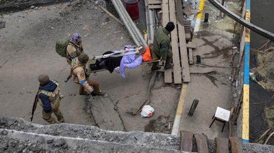 Personas tratan de evacuar a un herido en Irpin, tras un tiroteo ruso, el 13 de marzo de 2022.