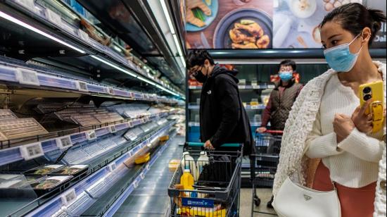 Varias personas compran comida en un supermercado casi vacío antes del confinamiento selectivo en Shanghái, el 25 de marzo de 2022.