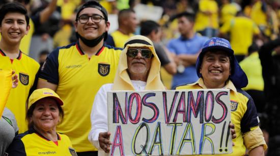 Fanáticos con un cartel de "nos vamos a Catar" en los graderíos del estadio Banco Pichincha.