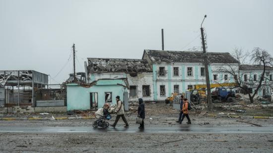 La gente pasa frente a una casa dañada en la ciudad de Makarev en la región de Kiev, la capital de Ucrania, el 1 de abril de 2022.