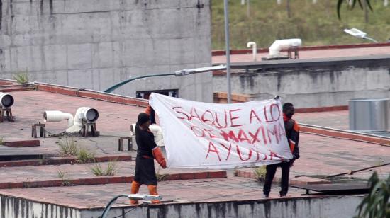 Dos personas privadas de la libertad (PPL) en la cárcel de Turi, en Cuenca, piden ayuda a la Policía y Fuerzas Armadas, el 3 de abril de 2022.