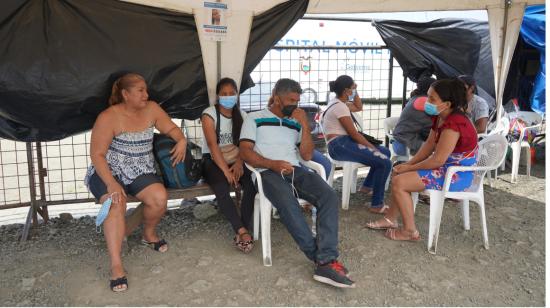 Familiares de pacientes esperan sobre la tierra y en una carpa afuera del hospital móvil en Pedernales, 7 de abril de 2022.