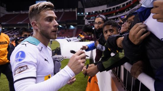 Ezequiel Piovi firma autógrafos después del partido de Liga ante Antofagasta, en el estadio Rodrigo Paz Delgado, el 12 de abril de 2022.