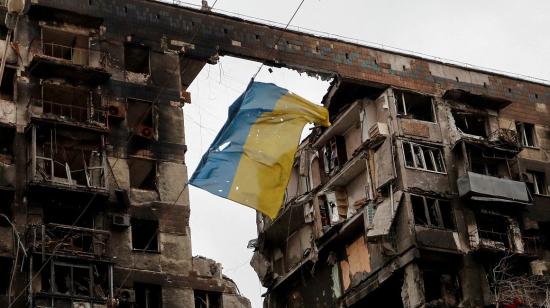 Una bandera de Ucrania cuelga entre dos edificios destruidos por bombardeos rusos en Mariúpol, el 17 de abril de 2022.