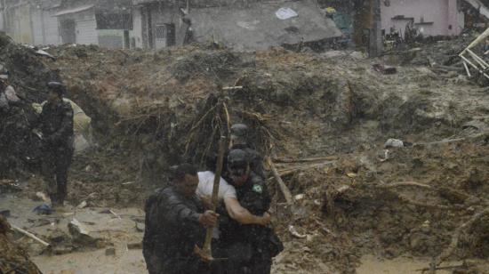 Soldados del Ejército impiden que una persona intente retirar el cuerpo de un familiar que fue enterrado en un deslizamiento de tierra provocado por fuertes lluvias en el barrio Jardim Monteverde de la ciudad de Jaboatão dos Guararapes, en Brasil, el 29 de mayo de 2022.