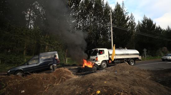 Vehículos se abren paso a un costado de la vía que ha sido bloqueada por manifestantes, en Cotopaxi, el 14 de junio de 2022.