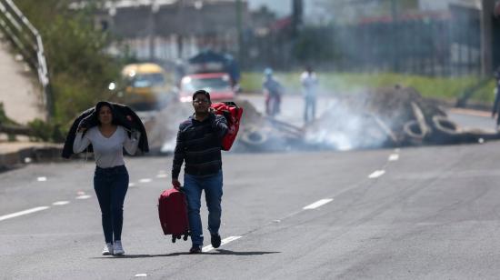 Dos personas caminan con maletas en una carretera que fue bloqueada al ingreso norte de Quito, el 13 de junio de 2022.