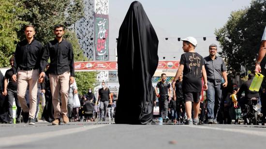 Una mujer cubierta con el velo o hiyab pasa junto a un grupo de hombres en Irán, el 17 de septiembre de 2022. 