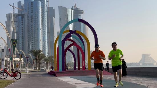 Personas trotan cerca de los coloridos arcos con la pancarta de la Copa Mundial en el Doha Corniche, el 6 de noviembre de 2022.