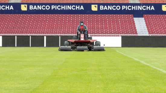 Un colaborador corta el césped del estadio Rodrigo Paz Delgado, propiedad de Liga de Quito.