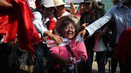 Una mujer lava la bandera de Perú durante una manifestación para pedir la liberación de Pedro Castillo, el 12 de diciembre de 2022, frente a la base de la Policía donde se encuentra recluido, en Lima.