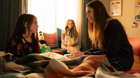 Las actrices Violet McGraw y Allison Williams aparecen en una escena de 'Megan'. Al medio, el robot-juguete está atento al diálogo.