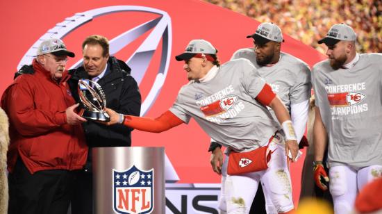 El mariscal de campo de los Kansas City Chiefs, Patrick Mahomes, entrega al head coach Andy Reid el Trofeo Lamar Hunt después de que los Chiefs derrotaran a los Cincinnati Bengals en el partido de Campeonato de la AFC.