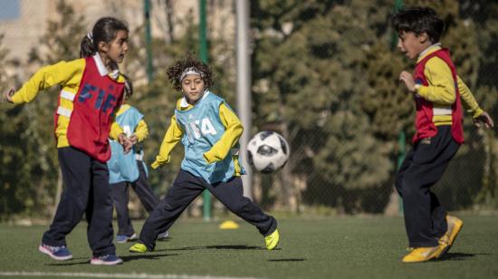 Niños juegan en una cancha de fútbol, en una escuela de la FIFA. 