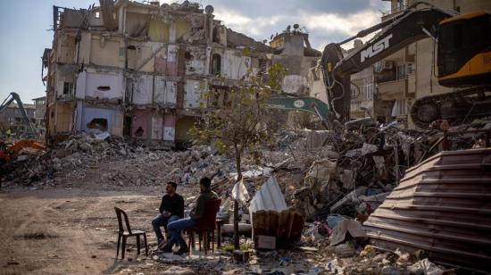 Ciudadanos turcos descansan frente a los escombros, en la ciudad de Hatay.