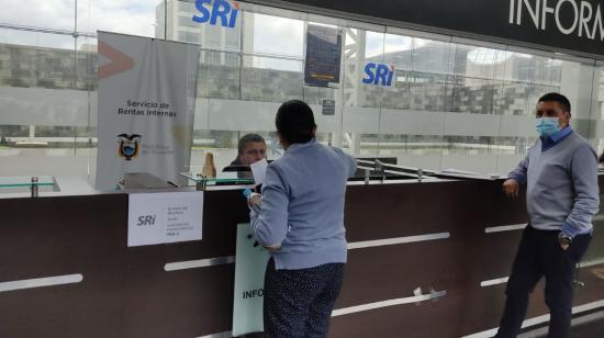 Personas hacen fila en la ventanilla de atención del Servicio de Rentas Internas (SRI) en la Plataforma Financiera, en el norte de Quito.