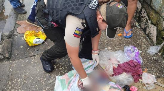 Una agente de la Policía en momentos en que encuentra a la bebé recién nacida en Guayaquil, el 14 de marzo de 2023. 