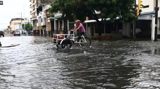 Una persona intenta cruzar una calle del sur de Guayaquil en su tricimoto, el 23 de abril de 2023.