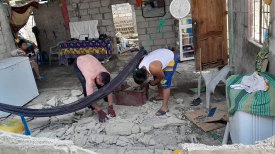 Dos hombres recogen destrozos una casa de Puerto Salinas, en el Golfo de Guayaquil, tras el terremoto del 18 de marzo. 