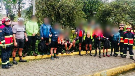 Ciclistas rescatados en Mindo posan con miembros del Cuerpo de Bomberos y la Policía.