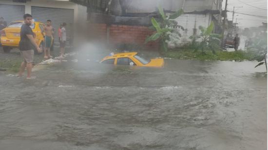 El auto de un taxista quedó atrapado en el agua en Bastión Popular, Guayaquil, el 16 de abril de 2023. 