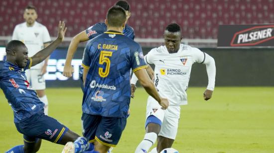 José Angulo, de Liga, maneja una pelota ante la marca de jugadores de Delfín, en Quito, el 8 de mayo de 2023.