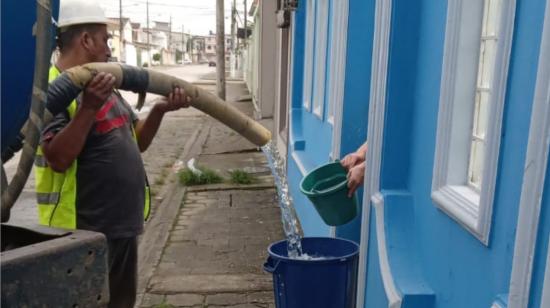 Un trabajador de Interagua entrega agua en una casa de Guayaquil, tras la suspensión del servicio, en abril de 2023. 