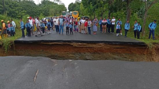 Varios pasajeros parados junto al socavón, formado en una vía de Muisne, Esmeraldas, el 10 de julio de 2023.