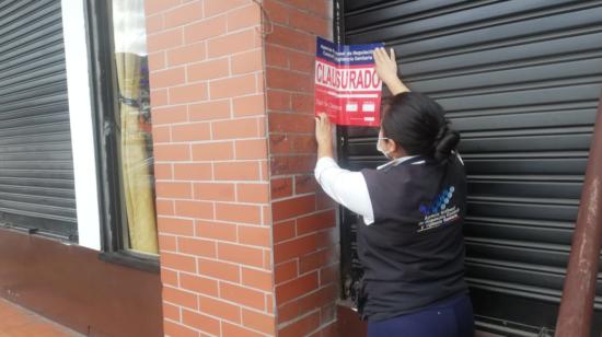 Una representante de la Arcsa realiza la clausura de un chifa en Quito, el 31 de julio de 2023.