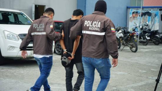 El detenido por el secuestro de la decana de Medicina en Guayaquil es escoltado por dos policías, el 10 de agosto de 2023. 