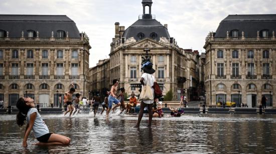 Los niños se refrescan mientras corren sobre una fina capa de agua en el Mirroir d'Eau a lo largo del río Garona, en Burdeos, suroeste de Francia, el 23 de agosto de 2023.