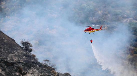 Un helicóptero del Cierpo de Bomberos de Quito realiza una descarga de agua en el sector de Itulcachi, el 1 de septiembre de 2023.