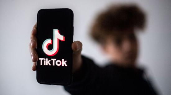 Un joven sostiene un celular con el logo de TikTok.