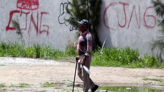 Un hombre pasa junto a un grafiti alusivo al cartel del narcotráfico Jalisco Nueva Generación, en México, el 29 de agosto de 2023.