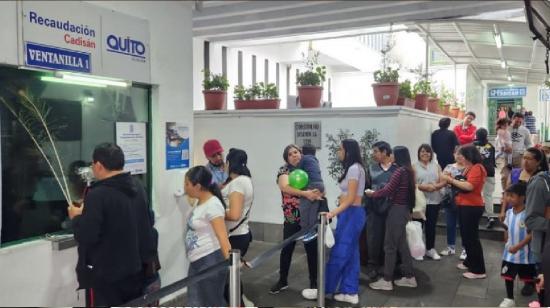 Usuarios hacen fila para pagar en el estacionamiento Cadisan, centro de Quito.