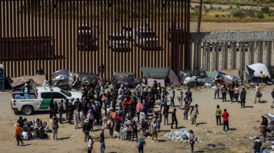 Fotografía general donde se observa a migrantes en un campamento junto al muro fronterizo, en Tijuana, Baja California (México).