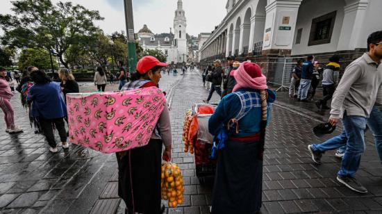 Dos mujeres indígenas venden frutas en el centro de Quito, el 15 de agosto de 2023. 