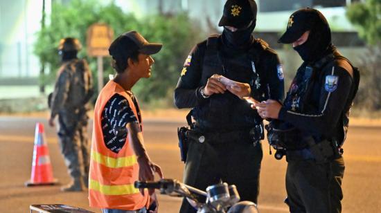 Dos policías verifican los documentos a un hombre a bordo de una moto, en Durán, cantón de Guayas, azotado por la violencia criminal, el 8 de octubre de 2023. 