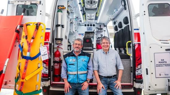 El ministro de Salud, José Ruales, junto al presidente Guillermo Lasso, sentados en la puerta de una de las nuevas ambulancias, entregadas en Manta, el 19 de octubre de 2023.