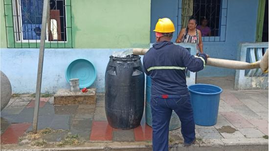 Un trabajador de Interagua entrega el agua a través de un tanquero en un sector de Guayaquil, el 28 de agosto de 2023.