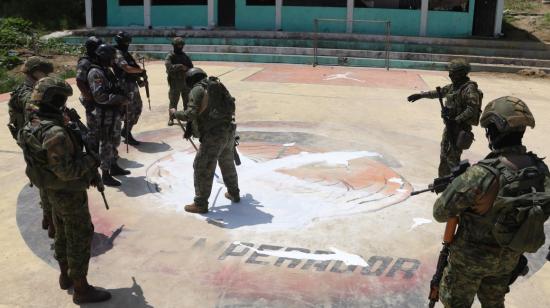 Un grupo de policías y militares borran un tigre de Los Tiguerones en el piso de una cancha deportiva en Esmeraldas, en abril del 2023. 