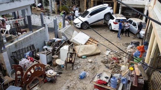 Personas quitan el lodo de sus muebles, junto a varios vehículos que fueron arrastrados por la corriente en Santo Domingo, República Dominicana.