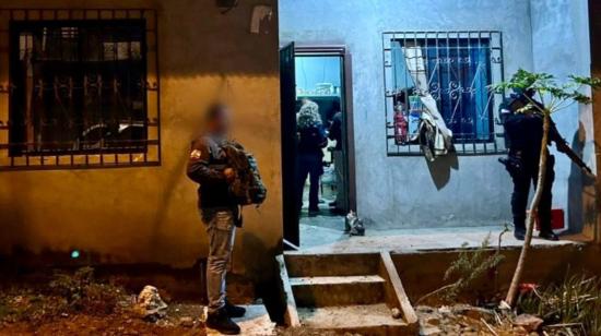 Dos policías en los exteriores de una vivienda allanada, durante la captura de 12 sujetos en Guayaquil, el 30 de noviembre de 2023.