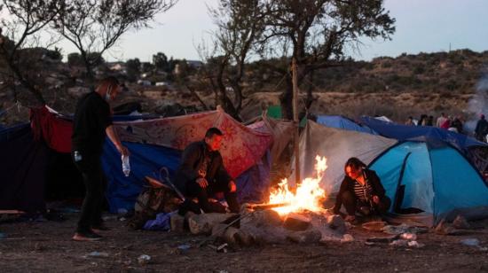 Los migrantes intentan mantenerse calientes junto a un fuego encendido cerca de la valla fronteriza entre Estados Unidos y México en Jacumba, California, el 6 de diciembre de 2023.