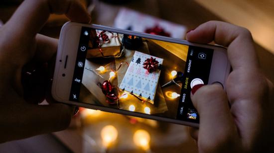 Imagen referencial de una persona tomando una fotografía a un regalo en Navidad.