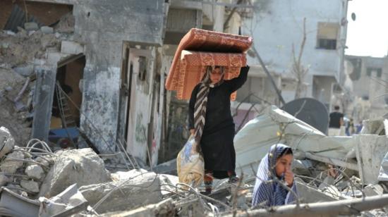 Una mujer y su hija rescatan sus últimas pertenencias de un barrio bombardeado en Gaza.